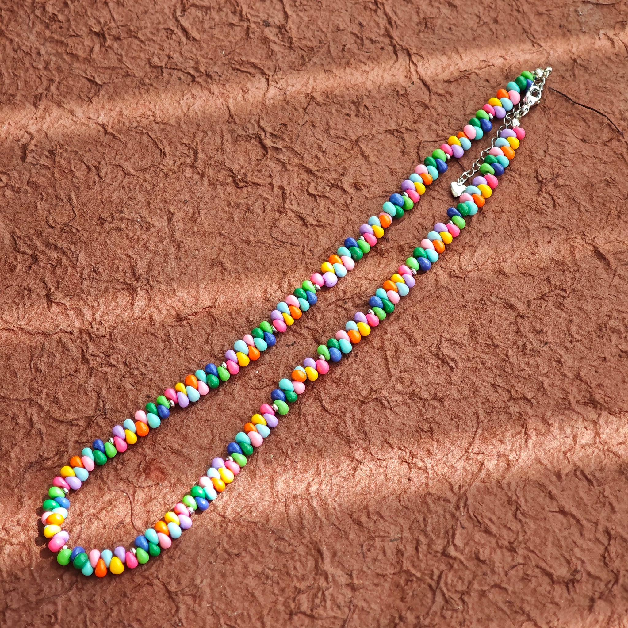 This is a bead necklace that consists of colorful peanut shape beads. It's as colorful as rainbow.