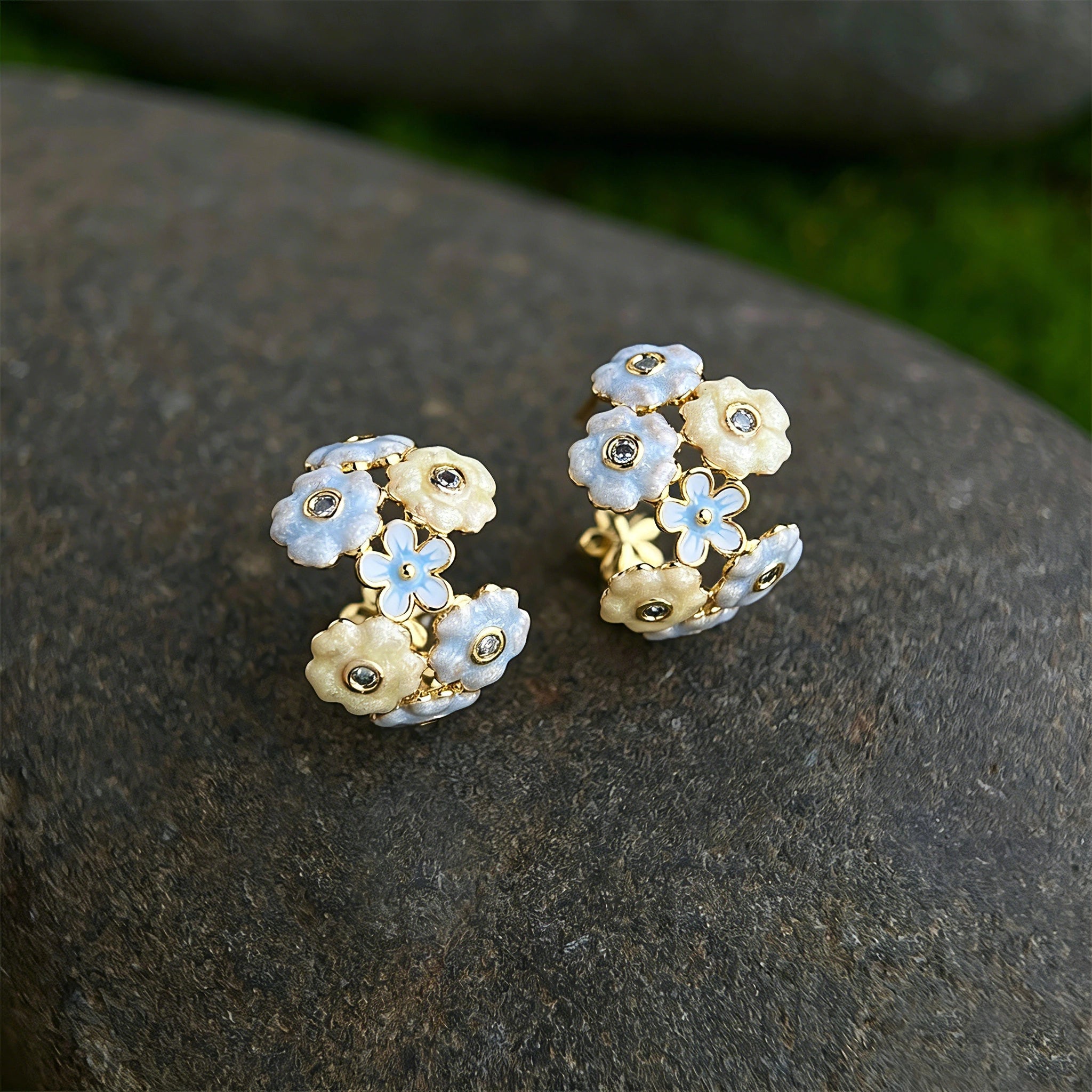 These 18k gold-plated stud/clip earrings feature delicate blossoms crafted with enamel glaze and inlaid with sparkling zircon stones. The combination of soft blue, creamy yellow and lustrous gold creates a romantic and feminine look that captures the essence of blooming florals.