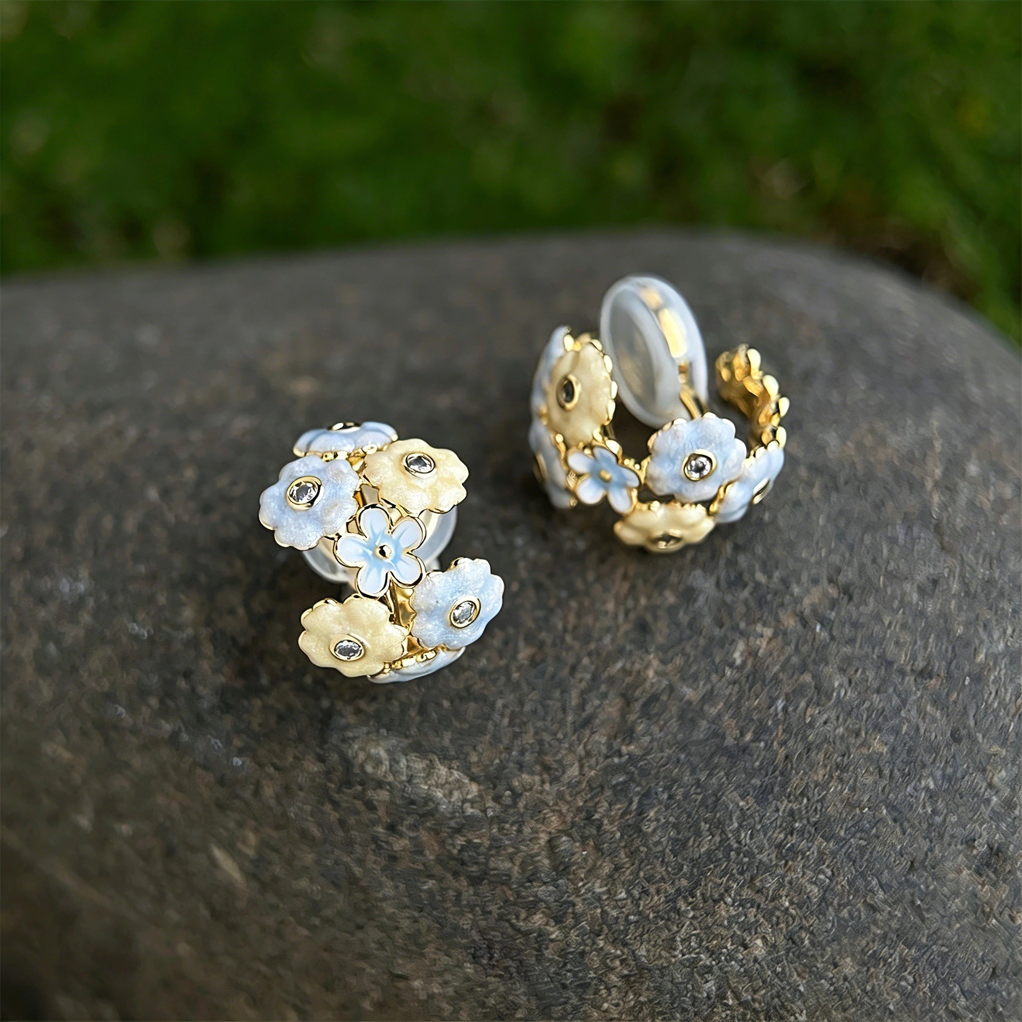 These 18k gold-plated stud/clip earrings feature delicate blossoms crafted with enamel glaze and inlaid with sparkling zircon stones. The combination of soft blue, creamy yellow and lustrous gold creates a romantic and feminine look that captures the essence of blooming florals.