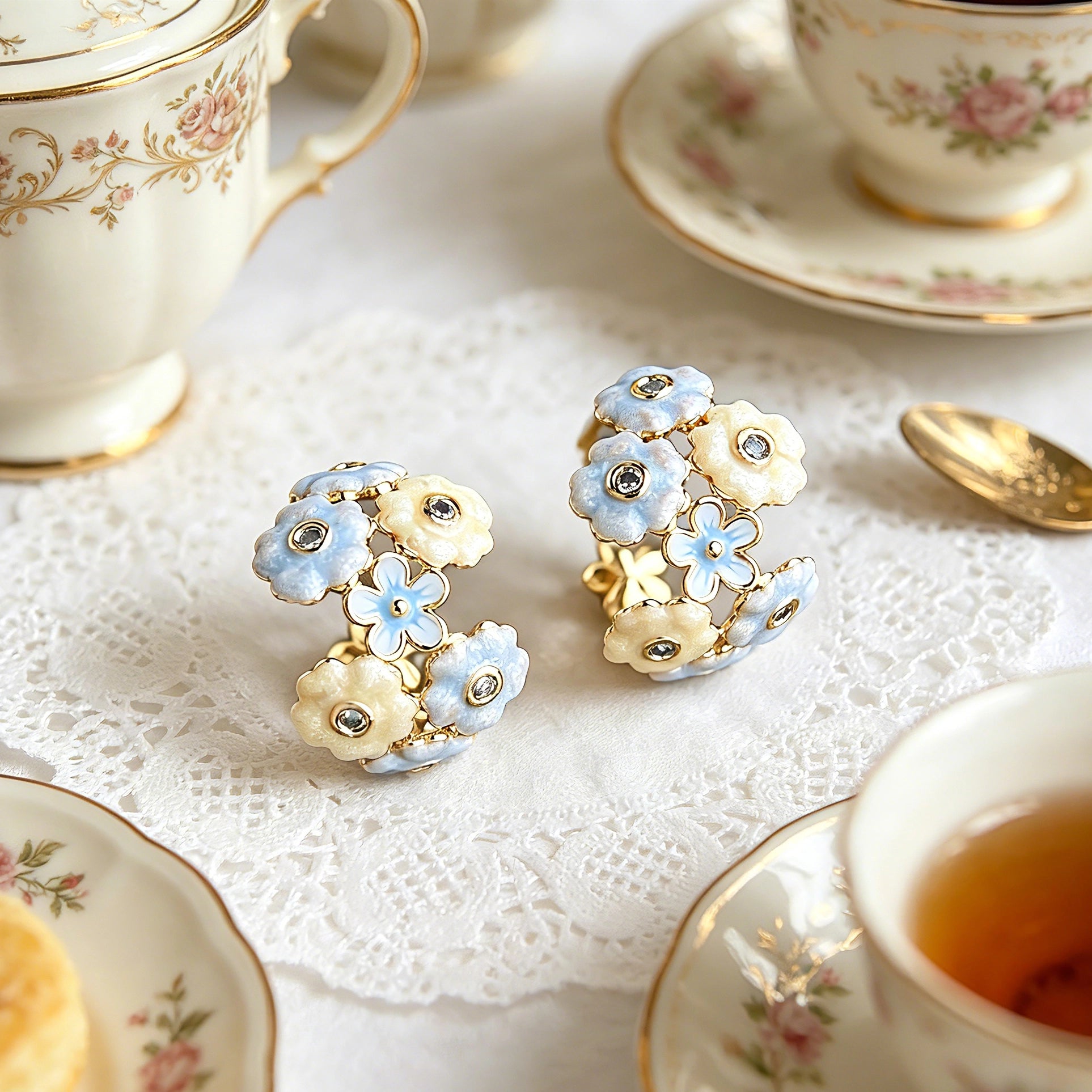 These 18k gold-plated stud/clip earrings feature delicate blossoms crafted with enamel glaze and inlaid with sparkling zircon stones. The combination of soft blue, creamy yellow and lustrous gold creates a romantic and feminine look that captures the essence of blooming florals.