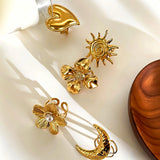 This 18K gold‑plated stainless steel ring set features bold sculpted designs of flowers, a puffy heart, swirling sun, and hammered crescent moon. Some flower rings are accented with a lustrous faux pearl for extra vintage charm. These open adjustable statement rings deliver a chunky retro aesthetic for everyday and special‑occasion styling.