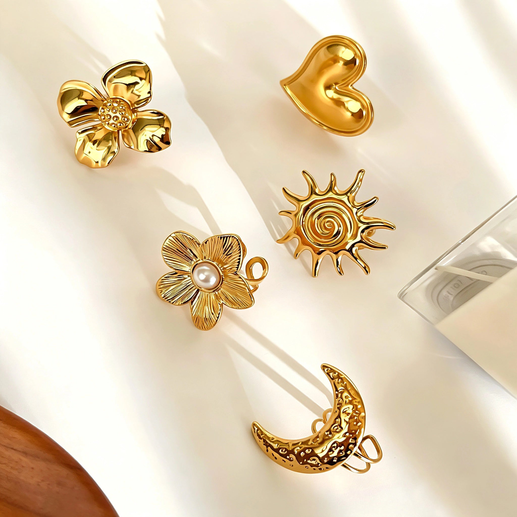 This 18K gold‑plated stainless steel ring set features bold sculpted designs of flowers, a puffy heart, swirling sun, and hammered crescent moon. Some flower rings are accented with a lustrous faux pearl for extra vintage charm. These open adjustable statement rings deliver a chunky retro aesthetic for everyday and special‑occasion styling.