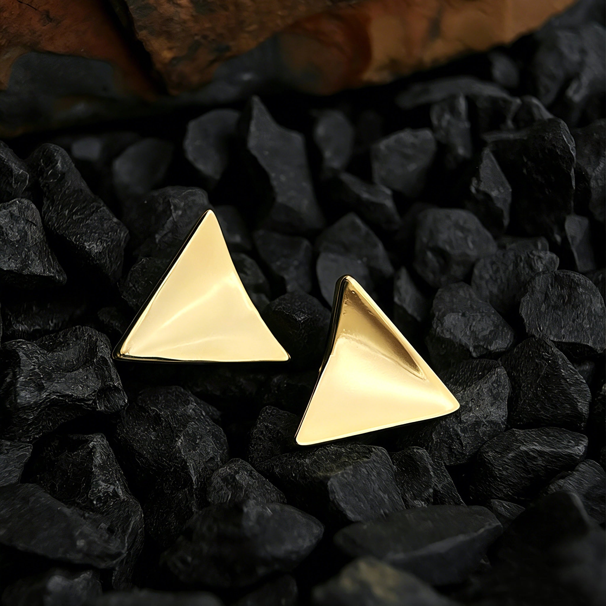 These thick 18K gold-plated stud earrings feature a sleek, modern curved triangle design with smooth, polished surfaces that catch the light beautifully. The sculpted, slightly concave shape creates a three-dimensional effect, adding subtle depth and dimension to the minimalist geometric silhouette.