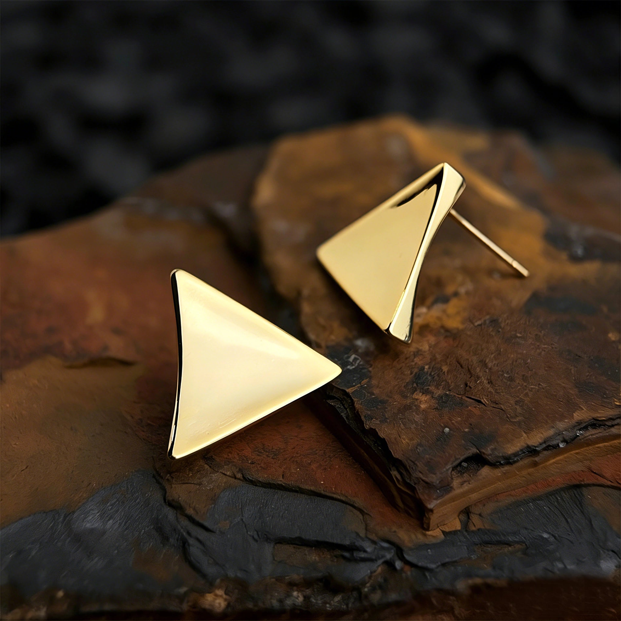 These thick 18K gold-plated stud earrings feature a sleek, modern curved triangle design with smooth, polished surfaces that catch the light beautifully. The sculpted, slightly concave shape creates a three-dimensional effect, adding subtle depth and dimension to the minimalist geometric silhouette.