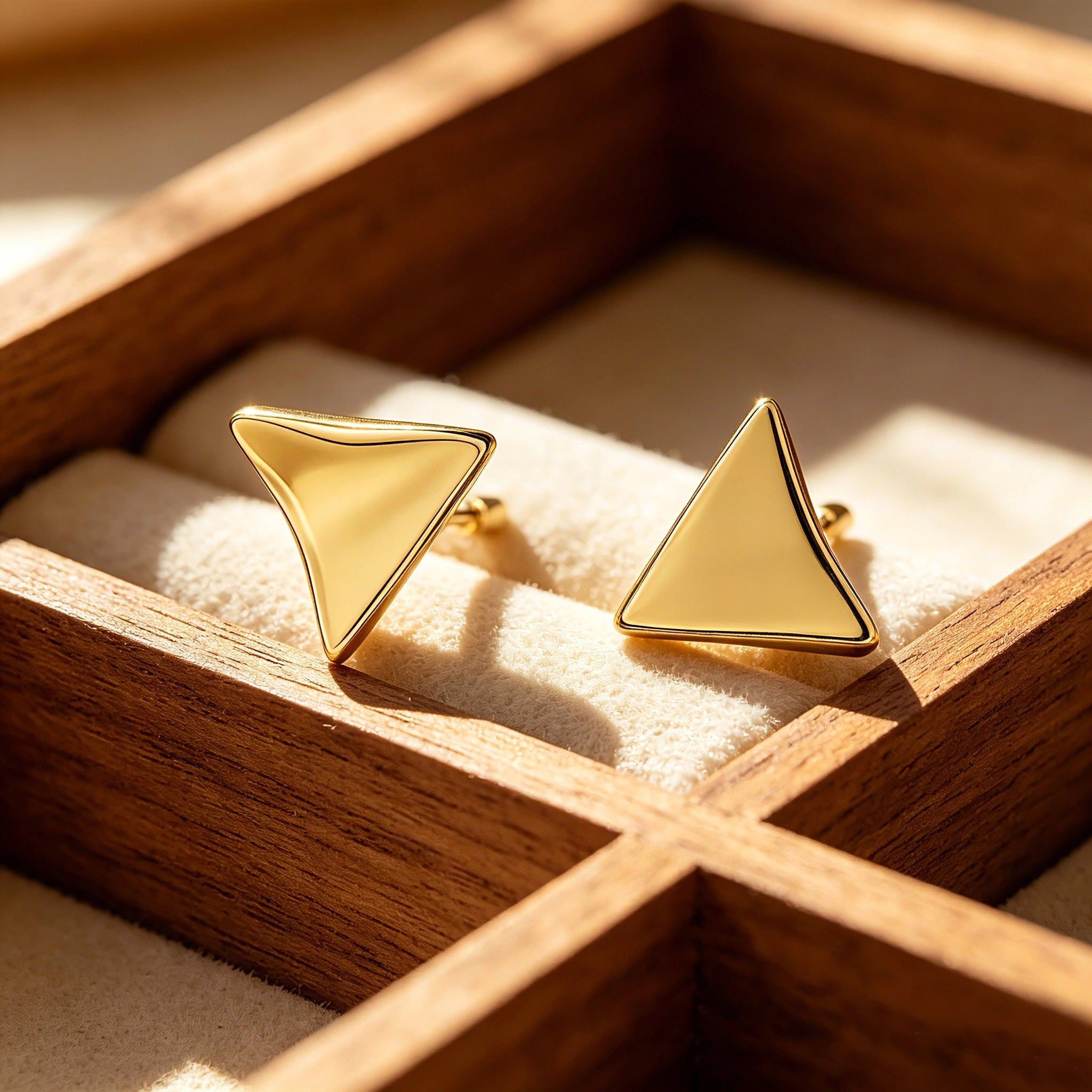 These thick 18K gold-plated stud earrings feature a sleek, modern curved triangle design with smooth, polished surfaces that catch the light beautifully. The sculpted, slightly concave shape creates a three-dimensional effect, adding subtle depth and dimension to the minimalist geometric silhouette.