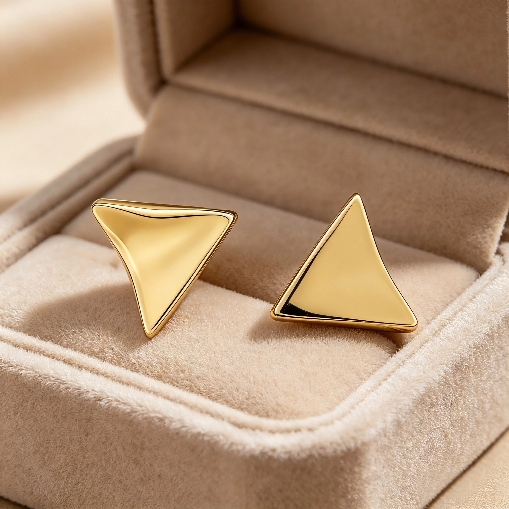 These thick 18K gold-plated stud earrings feature a sleek, modern curved triangle design with smooth, polished surfaces that catch the light beautifully. The sculpted, slightly concave shape creates a three-dimensional effect, adding subtle depth and dimension to the minimalist geometric silhouette.