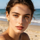 These thick 18K gold-plated stud earrings feature a sleek, modern curved triangle design with smooth, polished surfaces that catch the light beautifully. The sculpted, slightly concave shape creates a three-dimensional effect, adding subtle depth and dimension to the minimalist geometric silhouette.