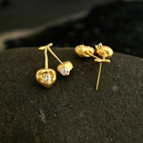 These cherry-shaped stud earrings feature a luxurious matte sandblasted finish, crafted from thick-plated real gold over 925 sterling silver posts. Each earring is designed as a pair of cherries, adorned with a marquise-cut and a round-cut sparkling clear stone, adding a delicate, eye-catching sparkle. The playful, organic cherry silhouette and premium gold plating make them a chic, elegant accessory for everyday wear.