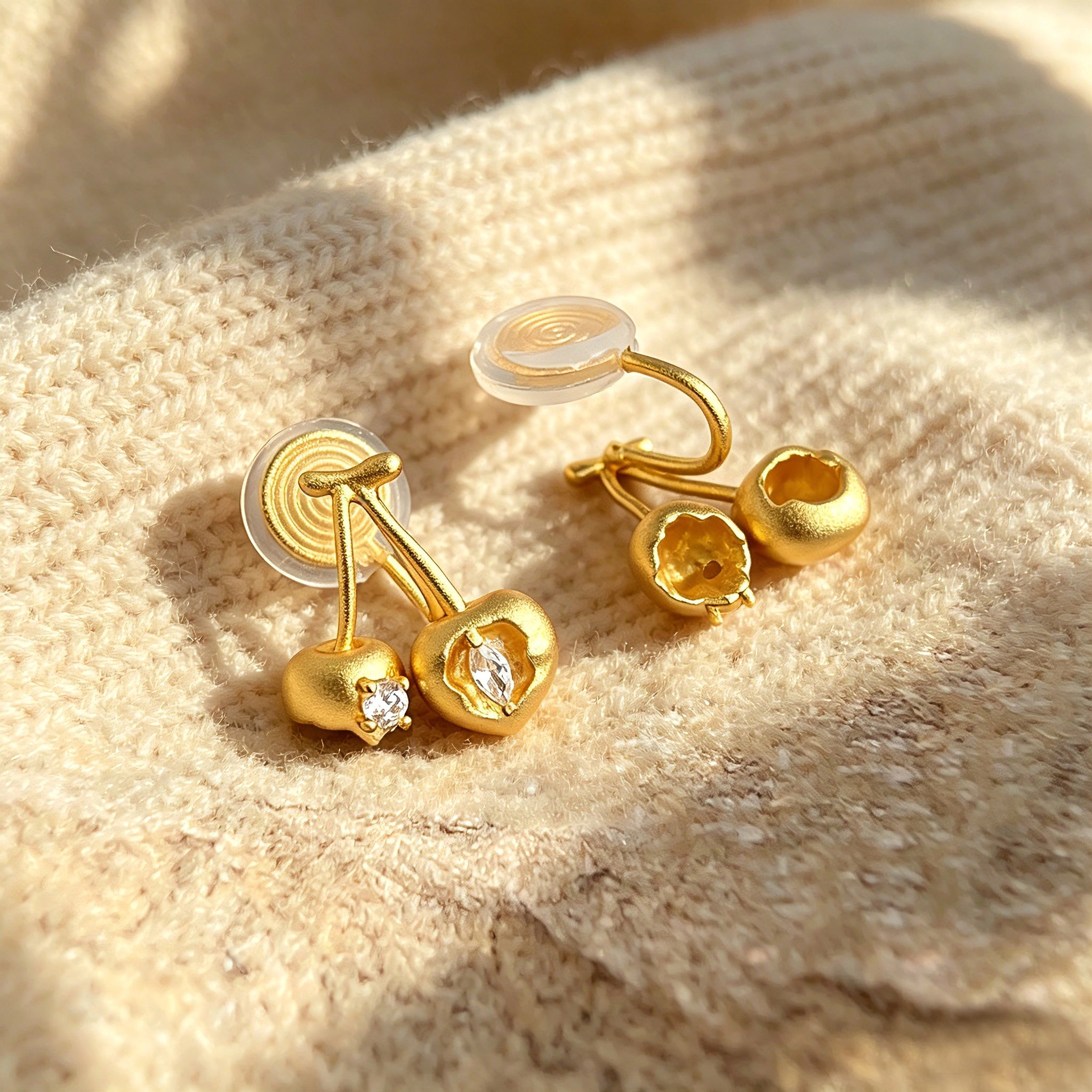 These cherry-shaped stud earrings feature a luxurious matte sandblasted finish, crafted from thick-plated real gold over 925 sterling silver posts. Each earring is designed as a pair of cherries, adorned with a marquise-cut and a round-cut sparkling clear stone, adding a delicate, eye-catching sparkle. The playful, organic cherry silhouette and premium gold plating make them a chic, elegant accessory for everyday wear.