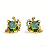 These stud earrings feature cushion-cut olive-green cubic zirconia stones, each encircled by delicate, nature-inspired gold floral and vine detailing. The thick 18K gold plating lends a rich, warm luster, contrasting beautifully with the deep green cubic zirconia to create an elegant, botanical aesthetic.
