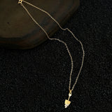 This is a necklace featuring a unique shovel-shaped pendant crafted with thick 18K gold plating, exuding a luxurious golden luster. The pendant is adorned with delicate micro-paved cubic zirconia stones, which sparkle brightly against the gold surface. Designed as a dainty pendant necklace, it showcases a sleek, minimalist style with intricate detailing on the shovel head and handle.