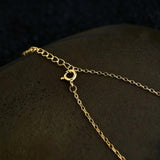 This is a necklace featuring a unique shovel-shaped pendant crafted with thick 18K gold plating, exuding a luxurious golden luster. The pendant is adorned with delicate micro-paved cubic zirconia stones, which sparkle brightly against the gold surface. Designed as a dainty pendant necklace, it showcases a sleek, minimalist style with intricate detailing on the shovel head and handle.