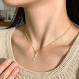 This is a necklace featuring a unique shovel-shaped pendant crafted with thick 18K gold plating, exuding a luxurious golden luster. The pendant is adorned with delicate micro-paved cubic zirconia stones, which sparkle brightly against the gold surface. Designed as a dainty pendant necklace, it showcases a sleek, minimalist style with intricate detailing on the shovel head and handle.