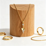 This is a necklace featuring a unique shovel-shaped pendant crafted with thick 18K gold plating, exuding a luxurious golden luster. The pendant is adorned with delicate micro-paved cubic zirconia stones, which sparkle brightly against the gold surface. Designed as a dainty pendant necklace, it showcases a sleek, minimalist style with intricate detailing on the shovel head and handle.