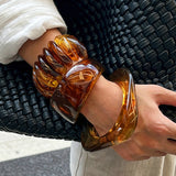Crafted from translucent acrylic, these amber marbled bangles feature organic swirling tones for a vintage aesthetic. The 3-piece set includes varied shapes that stack beautifully, adding earthy retro charm to any outfit. Smooth, polished surfaces deliver a lightweight, comfortable wearing experience.