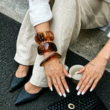 Crafted from translucent acrylic, these amber marbled bangles feature organic swirling tones for a vintage aesthetic. The 3-piece set includes varied shapes that stack beautifully, adding earthy retro charm to any outfit. Smooth, polished surfaces deliver a lightweight, comfortable wearing experience.