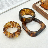 Crafted from translucent acrylic, these amber marbled bangles feature organic swirling tones for a vintage aesthetic. The 3-piece set includes varied shapes that stack beautifully, adding earthy retro charm to any outfit. Smooth, polished surfaces deliver a lightweight, comfortable wearing experience.