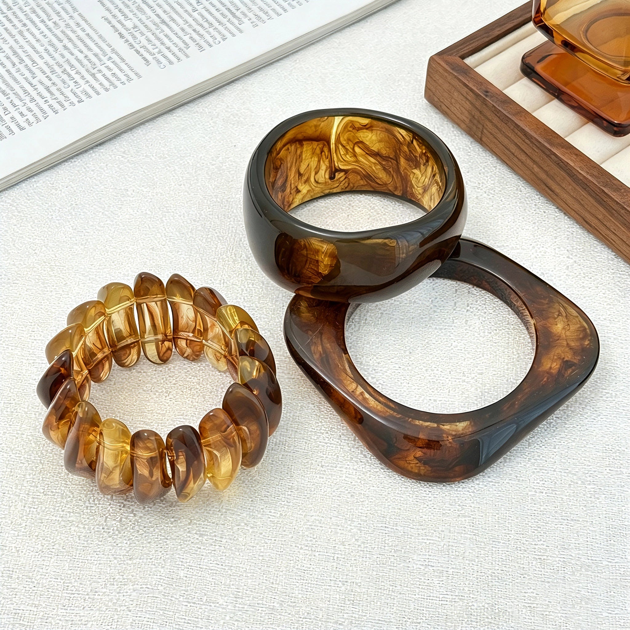 Crafted from translucent acrylic, these amber marbled bangles feature organic swirling tones for a vintage aesthetic. The 3-piece set includes varied shapes that stack beautifully, adding earthy retro charm to any outfit. Smooth, polished surfaces deliver a lightweight, comfortable wearing experience.