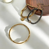 This vintage-inspired 3-piece bracelet set features a wavy gold bangle, engraved stainless steel bead chain and mixed black braided cord bracelet. Crafted from durable stainless steel, this stackable jewelry delivers timeless east-meets-west aesthetics for effortless layered styling. It is a versatile everyday accessory to elevate casual and chic outfits.