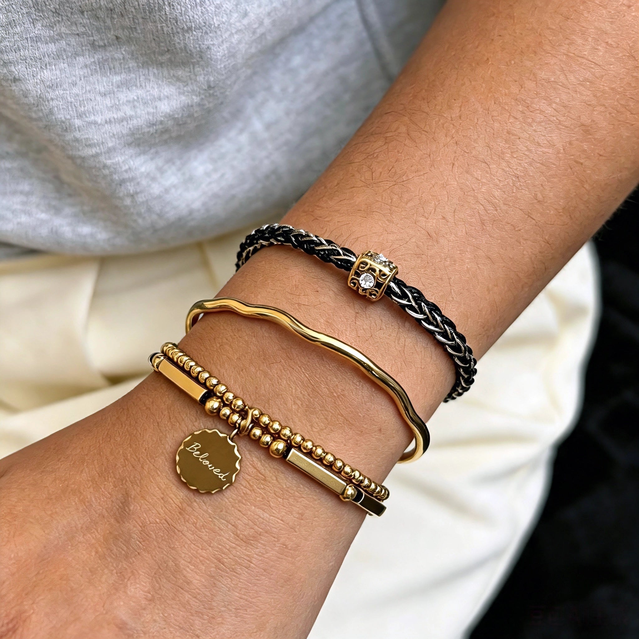This vintage-inspired 3-piece bracelet set features a wavy gold bangle, engraved stainless steel bead chain and mixed black braided cord bracelet. Crafted from durable stainless steel, this stackable jewelry delivers timeless east-meets-west aesthetics for effortless layered styling. It is a versatile everyday accessory to elevate casual and chic outfits.