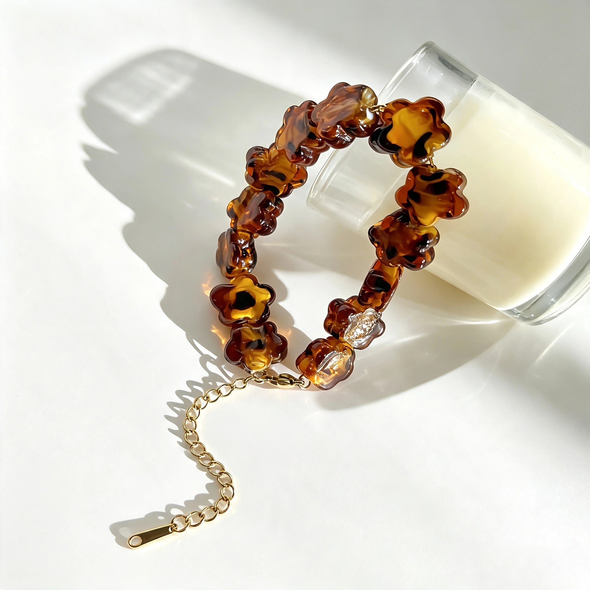 This 4-piece stackable bracelet set blends glossy tortoiseshell-pattern glass beads with polished stainless steel hardware. It includes flower-shaped, square, and oval beaded bracelets paired with a flexible gold-tone ribbed bangle. Perfect for layered styling, these warm earthy-toned accessories effortlessly elevate everyday and evening outfits.