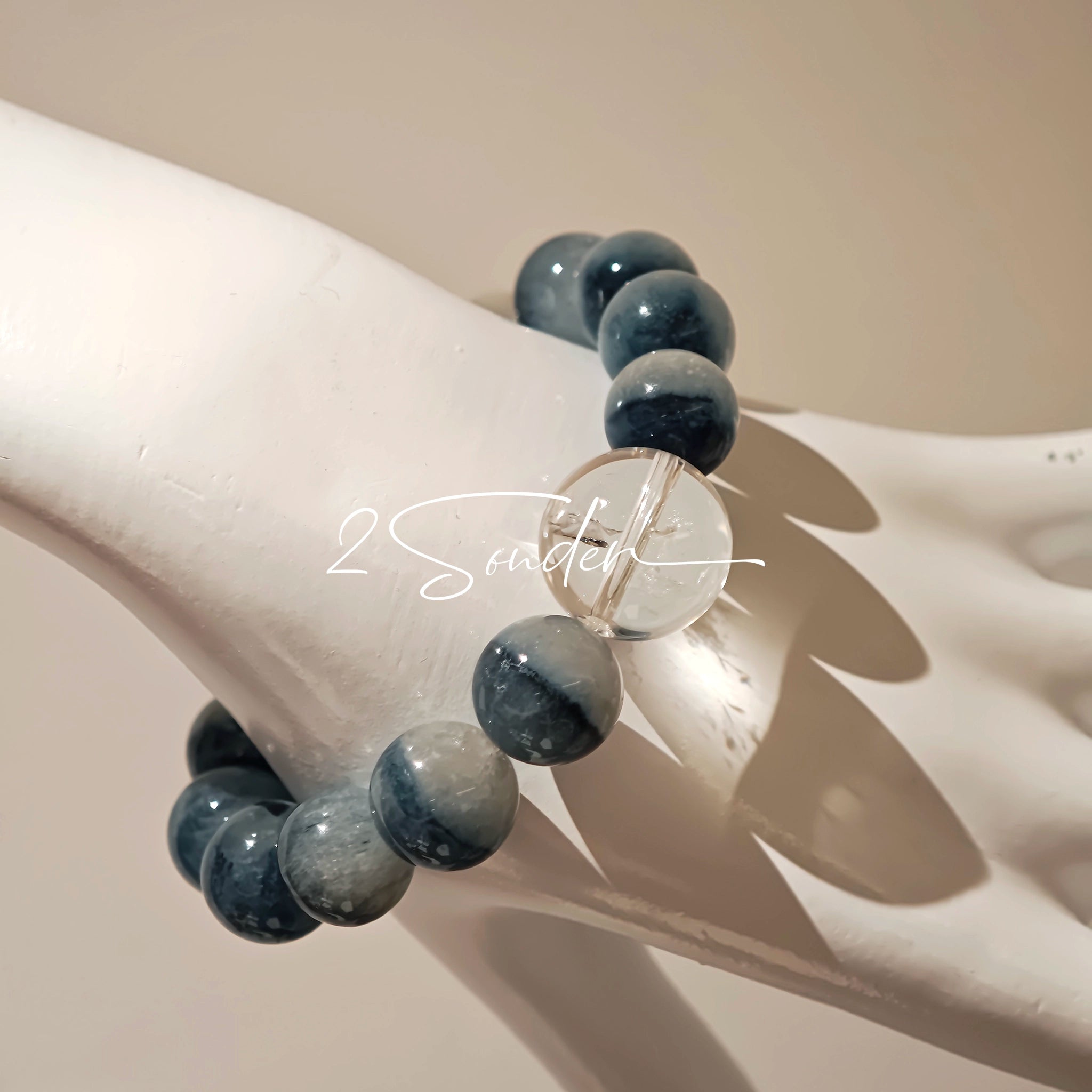 Blue rabbit hair and clear quartz beaded bracelet, featuring blue-gray rabbit hair quartz beads and a clear quartz focal bead, strung together in a circular design.