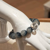 Blue rabbit hair and clear quartz beaded bracelet, featuring blue-gray rabbit hair quartz beads and a clear quartz focal bead, strung together in a circular design.