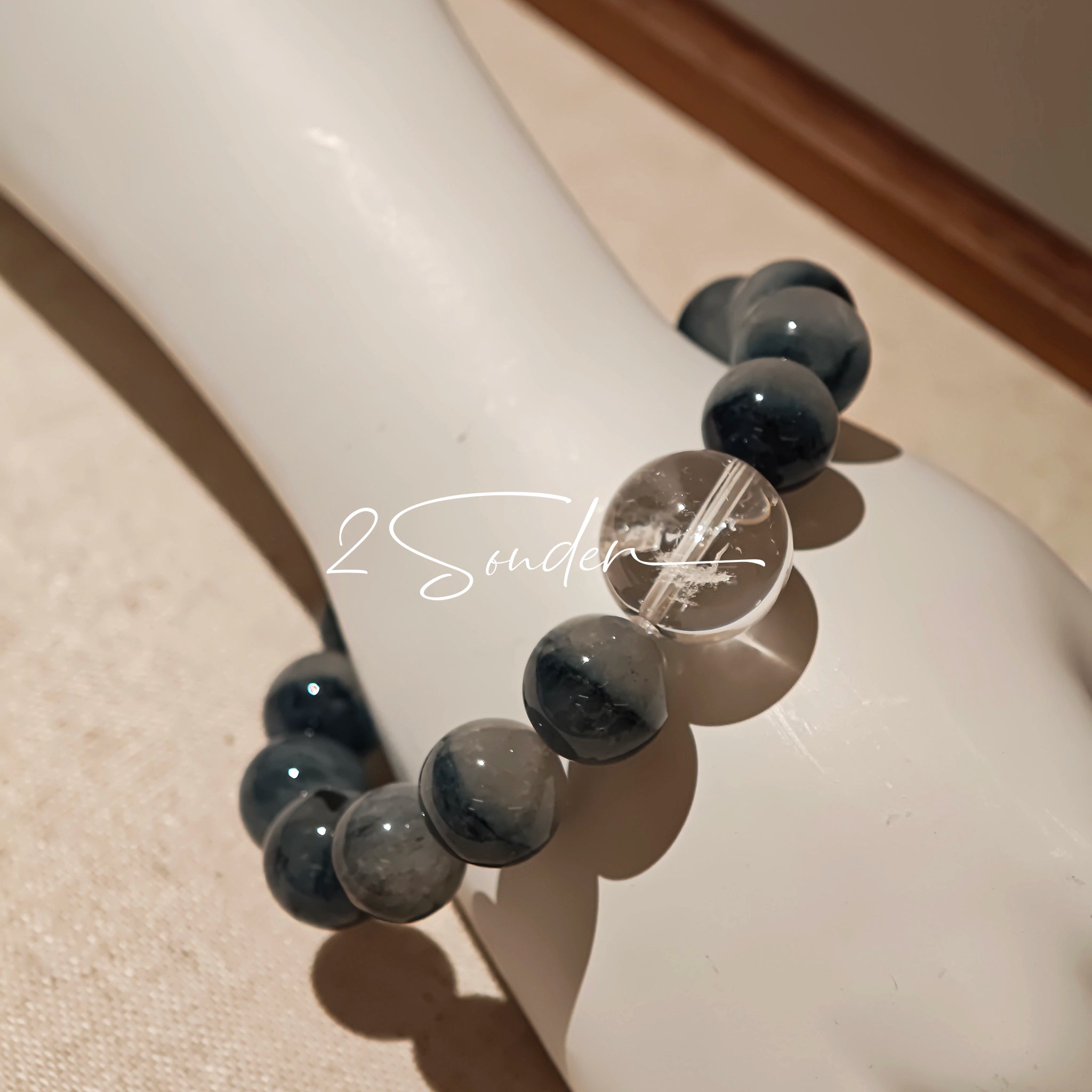 Blue rabbit hair and clear quartz beaded bracelet, featuring blue-gray rabbit hair quartz beads and a clear quartz focal bead, strung together in a circular design.