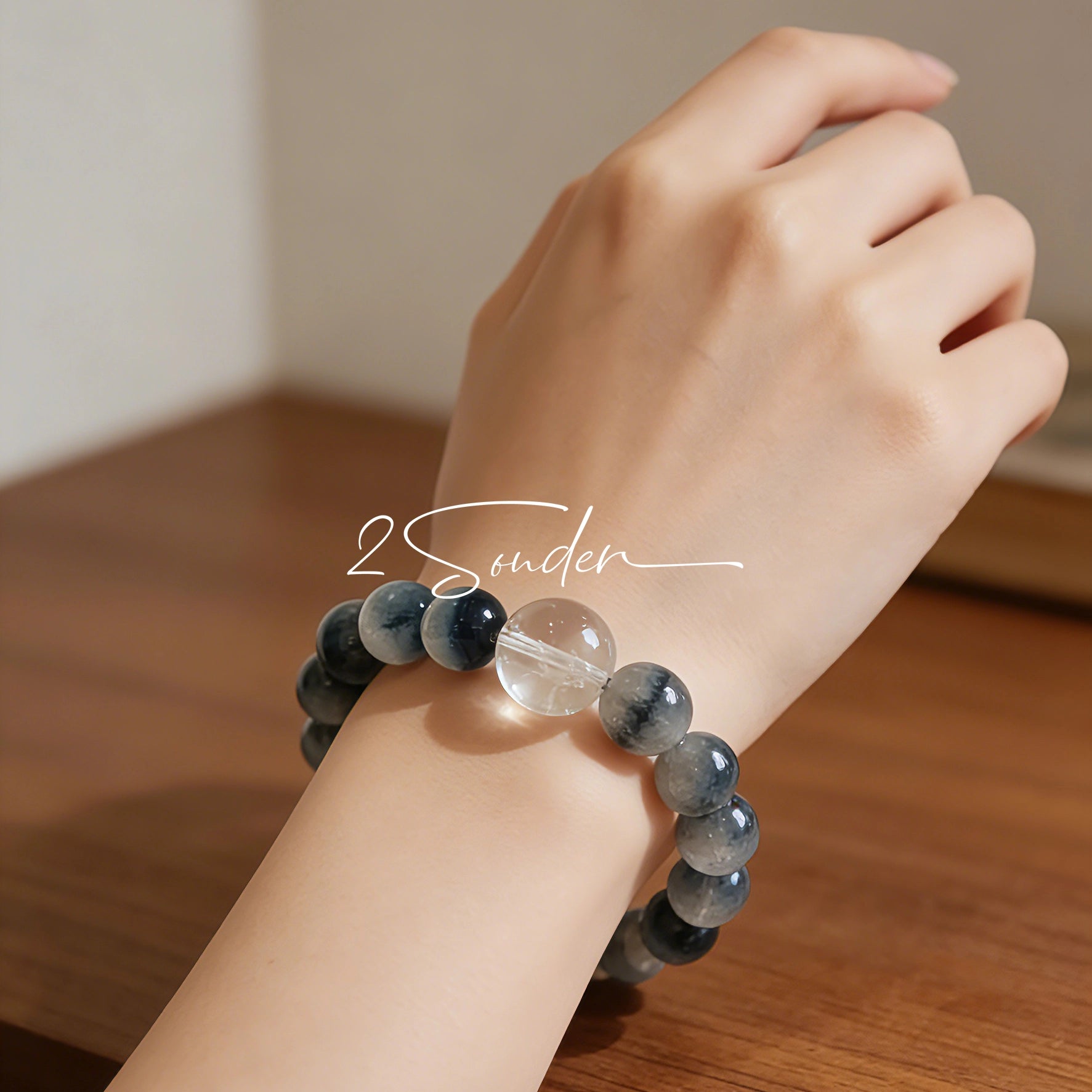 Blue rabbit hair and clear quartz beaded bracelet, featuring blue-gray rabbit hair quartz beads and a clear quartz focal bead, strung together in a circular design.