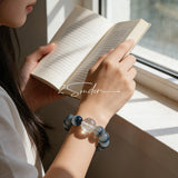 Blue rabbit hair and clear quartz beaded bracelet, featuring blue-gray rabbit hair quartz beads and a clear quartz focal bead, strung together in a circular design.