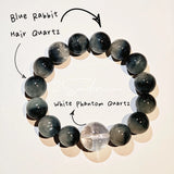 Blue rabbit hair and clear quartz beaded bracelet, featuring blue-gray rabbit hair quartz beads and a clear quartz focal bead, strung together in a circular design.
