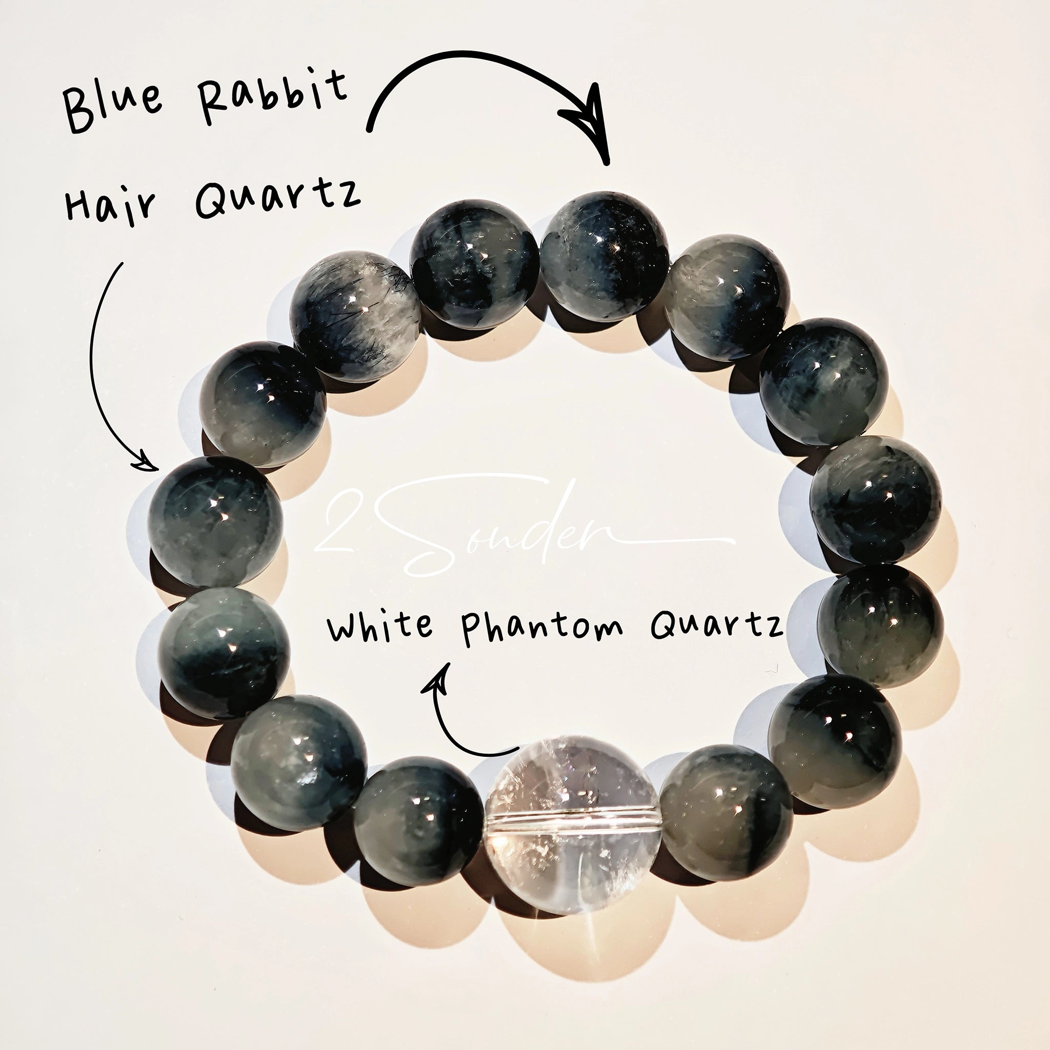 Blue rabbit hair and clear quartz beaded bracelet, featuring blue-gray rabbit hair quartz beads and a clear quartz focal bead, strung together in a circular design.