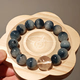 Blue rabbit hair and clear quartz beaded bracelet, featuring blue-gray rabbit hair quartz beads and a clear quartz focal bead, strung together in a circular design.