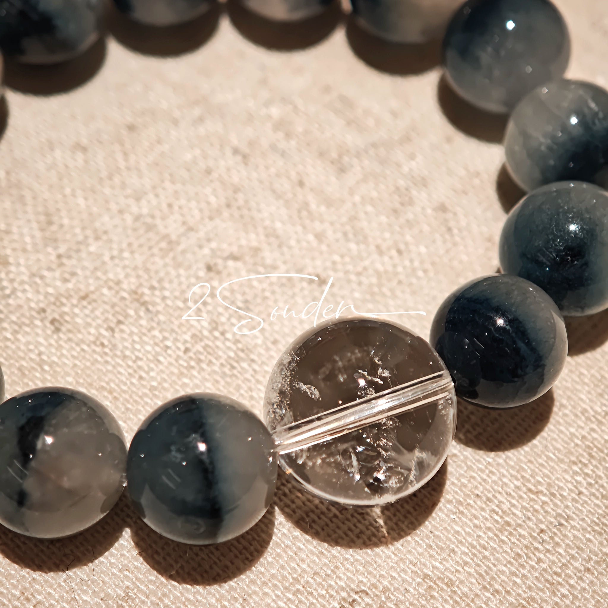 Blue rabbit hair and clear quartz beaded bracelet, featuring blue-gray rabbit hair quartz beads and a clear quartz focal bead, strung together in a circular design.