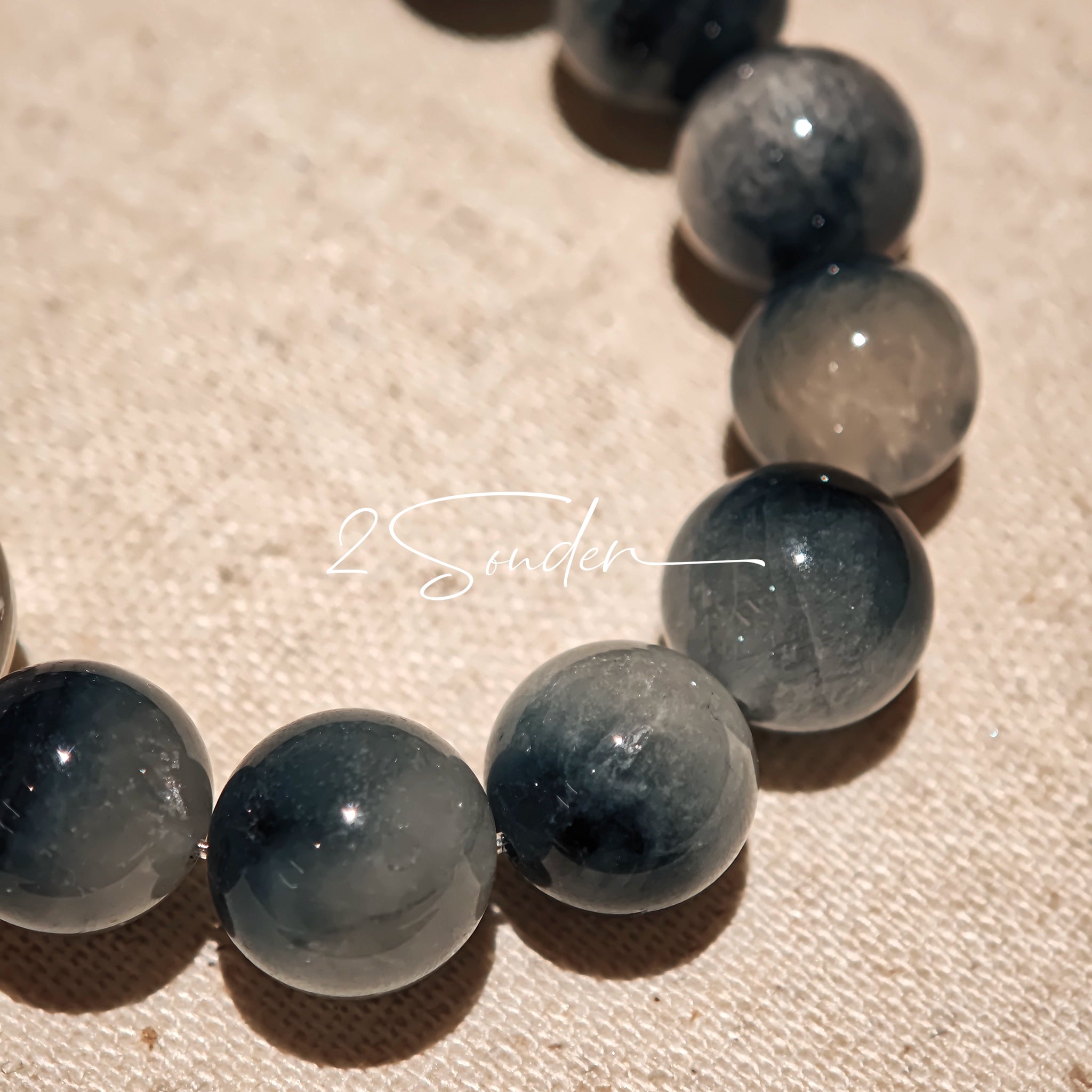 Blue rabbit hair and clear quartz beaded bracelet, featuring blue-gray rabbit hair quartz beads and a clear quartz focal bead, strung together in a circular design.