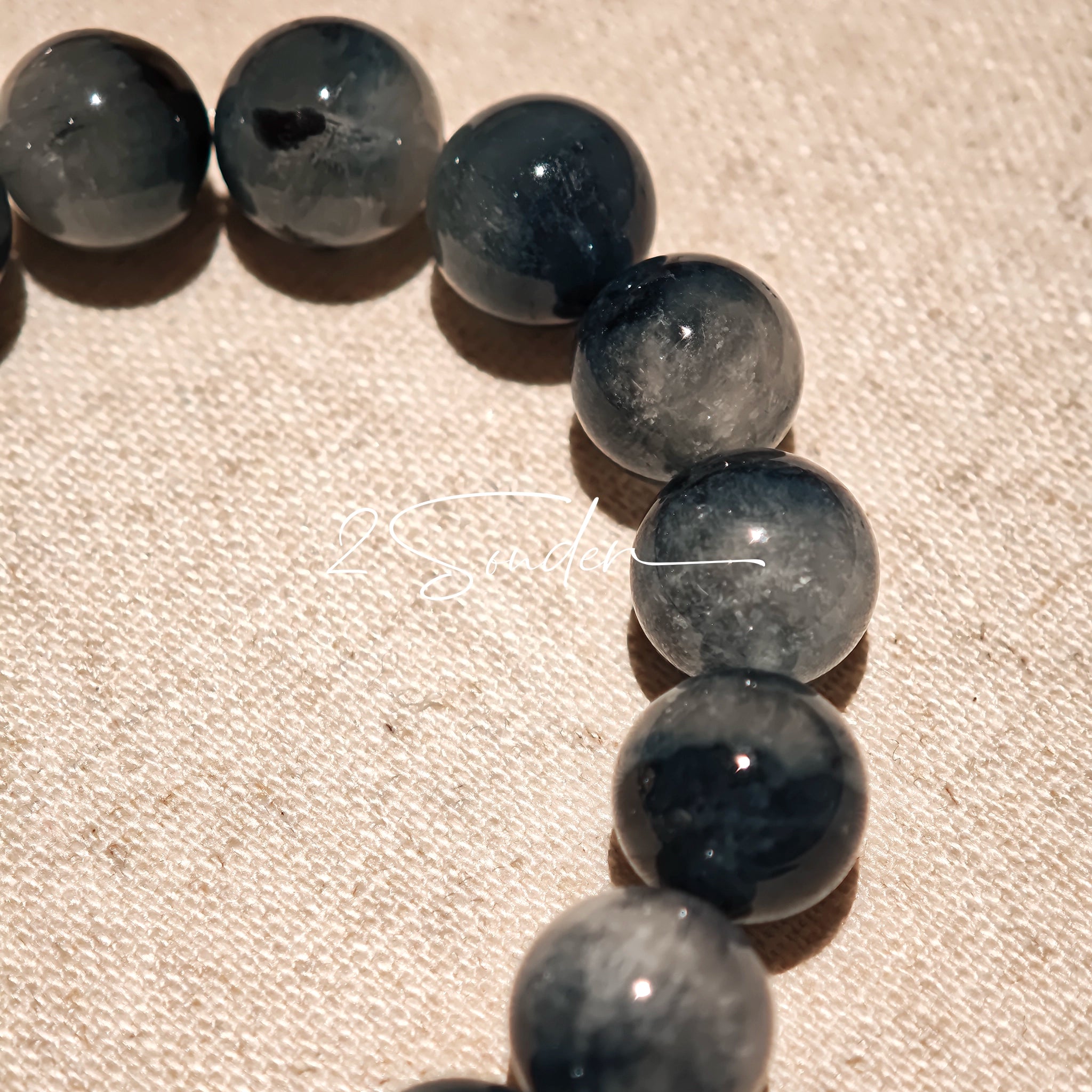 Blue rabbit hair and clear quartz beaded bracelet, featuring blue-gray rabbit hair quartz beads and a clear quartz focal bead, strung together in a circular design.