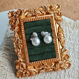 This minimalist pair of silver pearl stud earrings cleverly combine a chic silver heart-shaped pendant (11.7 mm wide) with a striking pearl teardrop (total height: 19.4 mm), with the pearl beneath the heart, creating a unique and stylish silhouette.