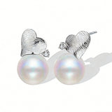 This minimalist pair of silver pearl stud earrings cleverly combine a chic silver heart-shaped pendant (11.7 mm wide) with a striking pearl teardrop (total height: 19.4 mm), with the pearl beneath the heart, creating a unique and stylish silhouette.