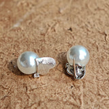 This minimalist pair of silver pearl stud earrings cleverly combine a chic silver heart-shaped pendant (11.7 mm wide) with a striking pearl teardrop (total height: 19.4 mm), with the pearl beneath the heart, creating a unique and stylish silhouette.