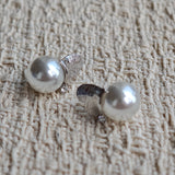 This minimalist pair of silver pearl stud earrings cleverly combine a chic silver heart-shaped pendant (11.7 mm wide) with a striking pearl teardrop (total height: 19.4 mm), with the pearl beneath the heart, creating a unique and stylish silhouette.