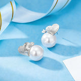 This minimalist pair of silver pearl stud earrings cleverly combine a chic silver heart-shaped pendant (11.7 mm wide) with a striking pearl teardrop (total height: 19.4 mm), with the pearl beneath the heart, creating a unique and stylish silhouette.