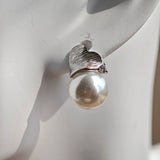 This minimalist pair of silver pearl stud earrings cleverly combine a chic silver heart-shaped pendant (11.7 mm wide) with a striking pearl teardrop (total height: 19.4 mm), with the pearl beneath the heart, creating a unique and stylish silhouette.