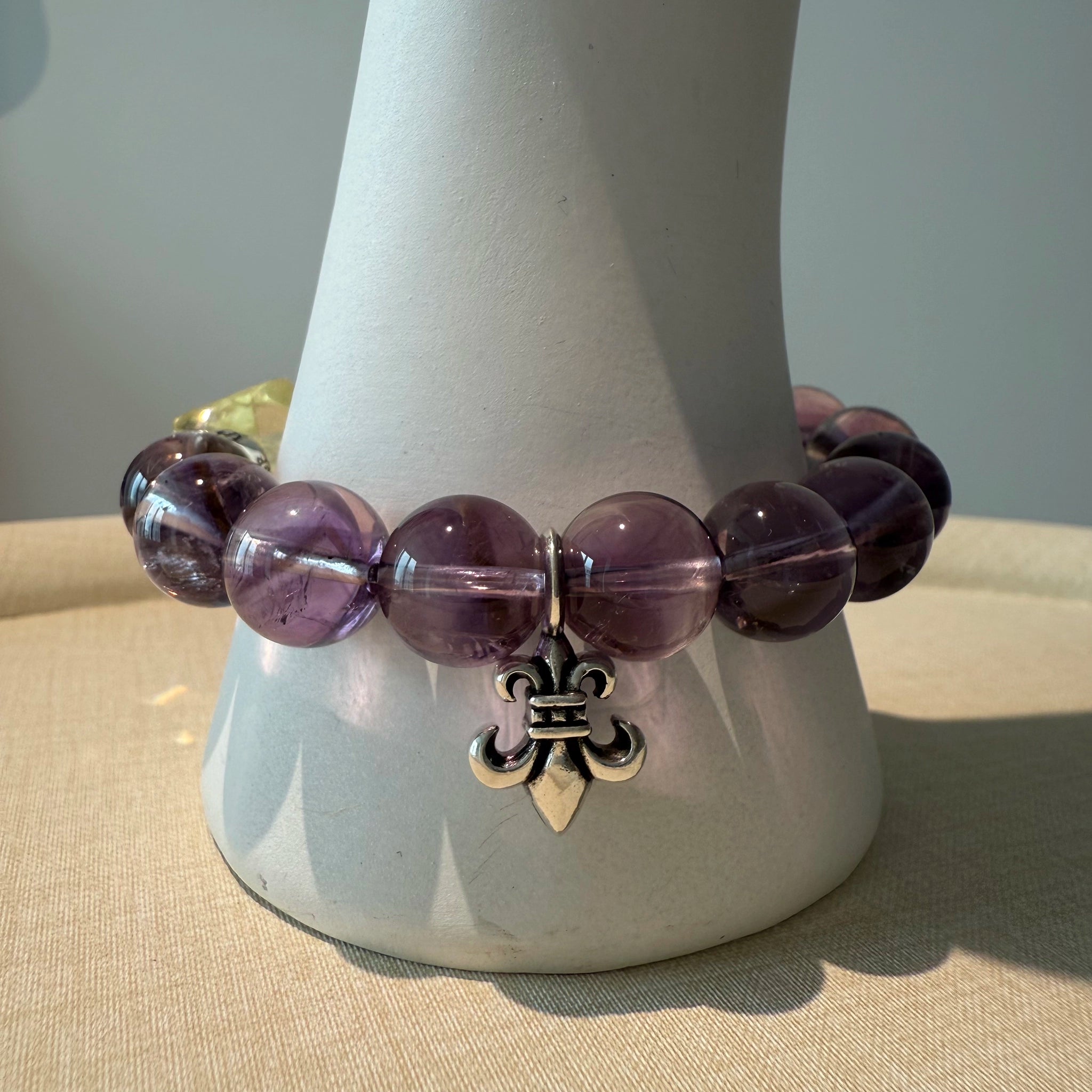 Fourteen amethyst petals surround one citrine pistil; sterling pollen floats around them—wearable flower of crystals on your wrist.