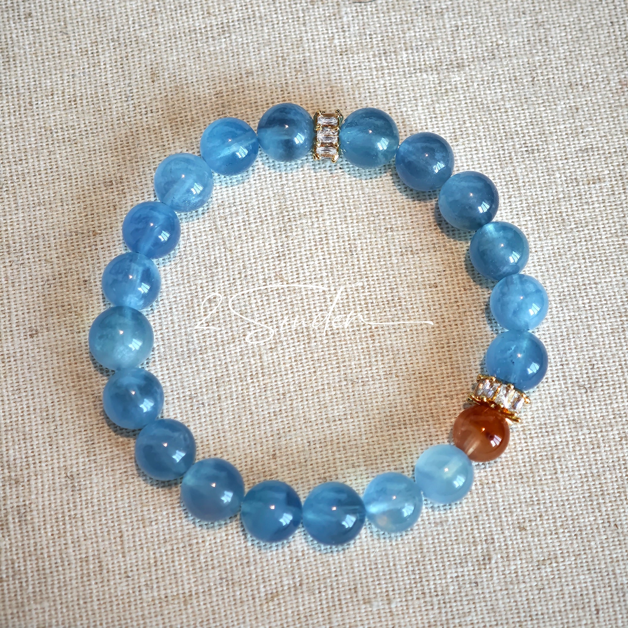 This is a gemstone bracelet that consists of 19pcs of 7-8mm aquamarine beads and 1pcs of red rutilated quartz. There are also 2 silver spacer beads in the bracelet. The main color of the bracelet is sky blue. The entire bracelet is translucent and beautiful.