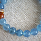 This is a gemstone bracelet that consists of 19pcs of 7-8mm aquamarine beads and 1pcs of red rutilated quartz. There are also 2 silver spacer beads in the bracelet. The main color of the bracelet is sky blue. The entire bracelet is translucent and beautiful.