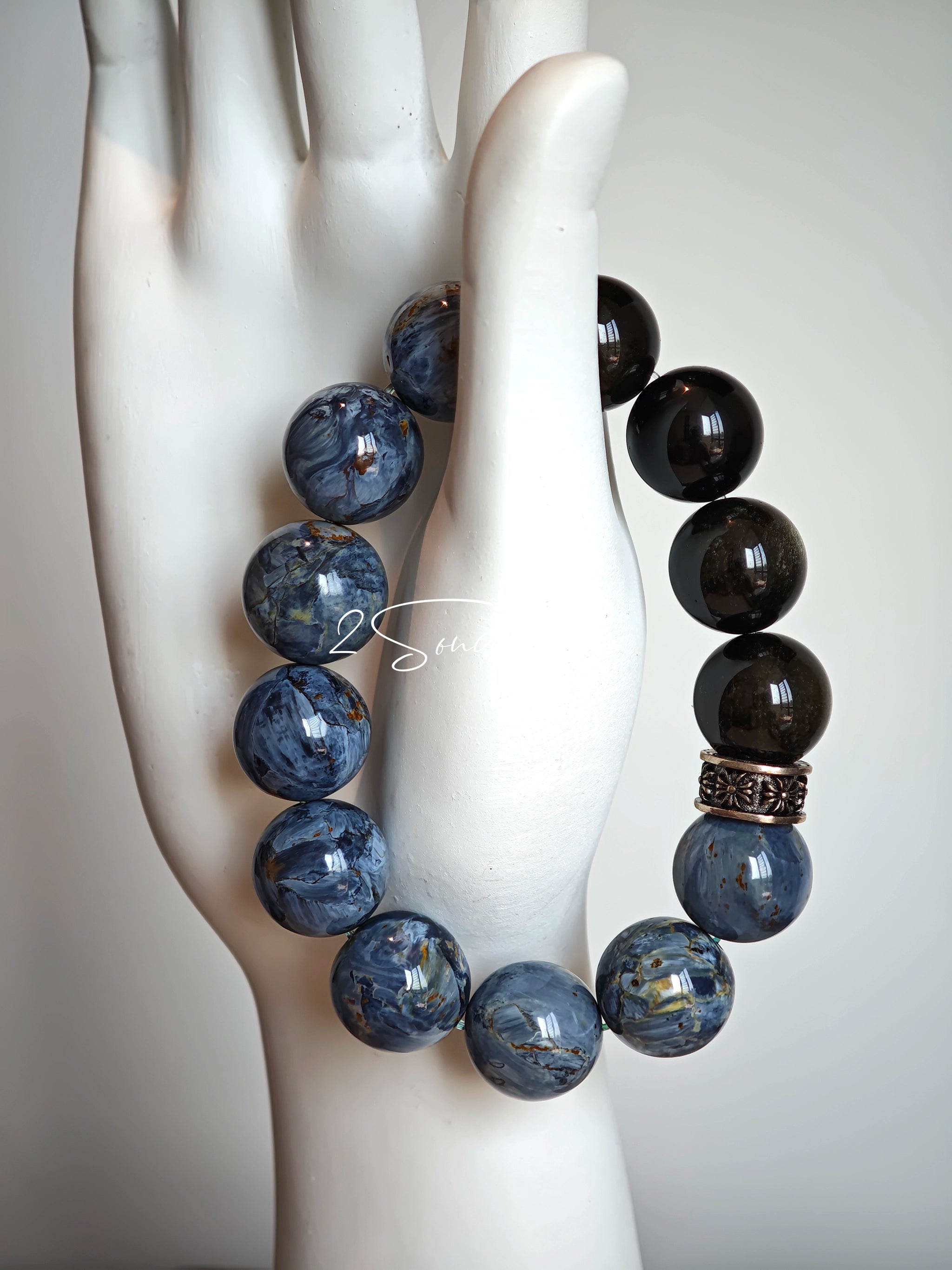 This is a bracelet consists of Blue Denim Pietersite and Golden Sheen Obsidian. The color of the bracelet is denim blue and black, accented by sleek silver spacer.