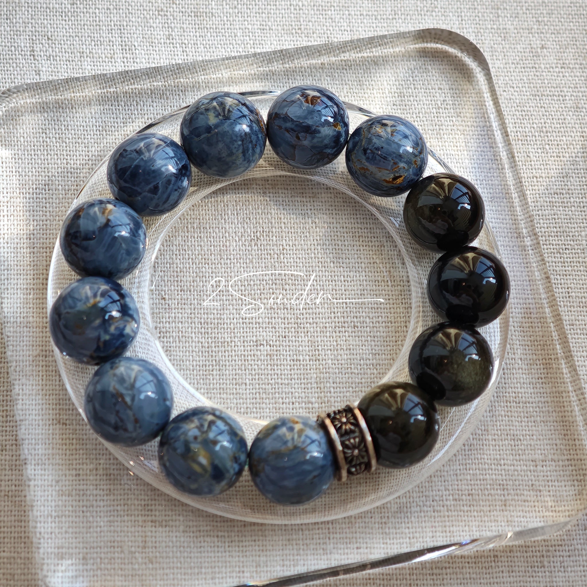 This is a bracelet consists of Blue Denim Pietersite and Golden Sheen Obsidian. The color of the bracelet is denim blue and black, accented by sleek silver spacer.