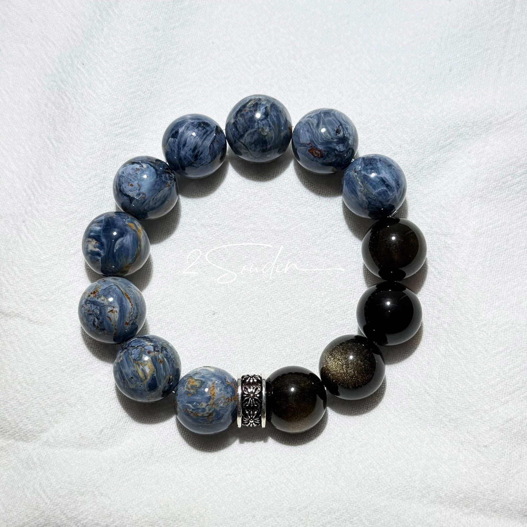 This is a bracelet consists of Blue Denim Pietersite and Golden Sheen Obsidian. The color of the bracelet is denim blue and black, accented by sleek silver spacer.