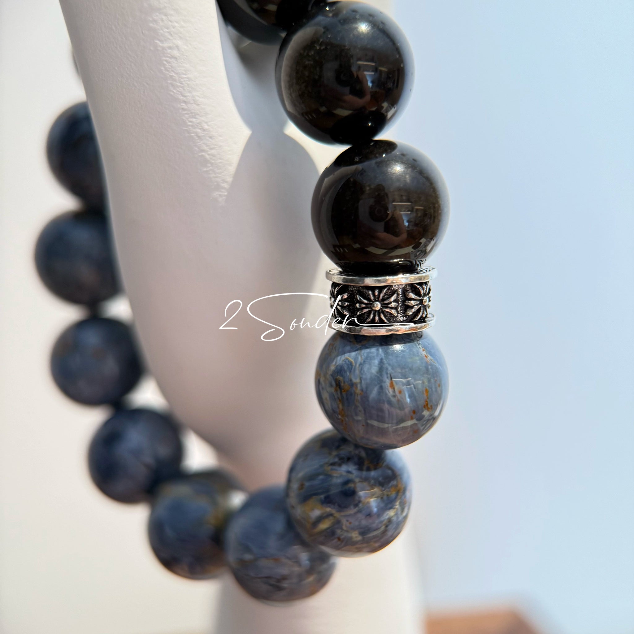 This is a bracelet consists of Blue Denim Pietersite and Golden Sheen Obsidian. The color of the bracelet is denim blue and black, accented by sleek silver spacer.