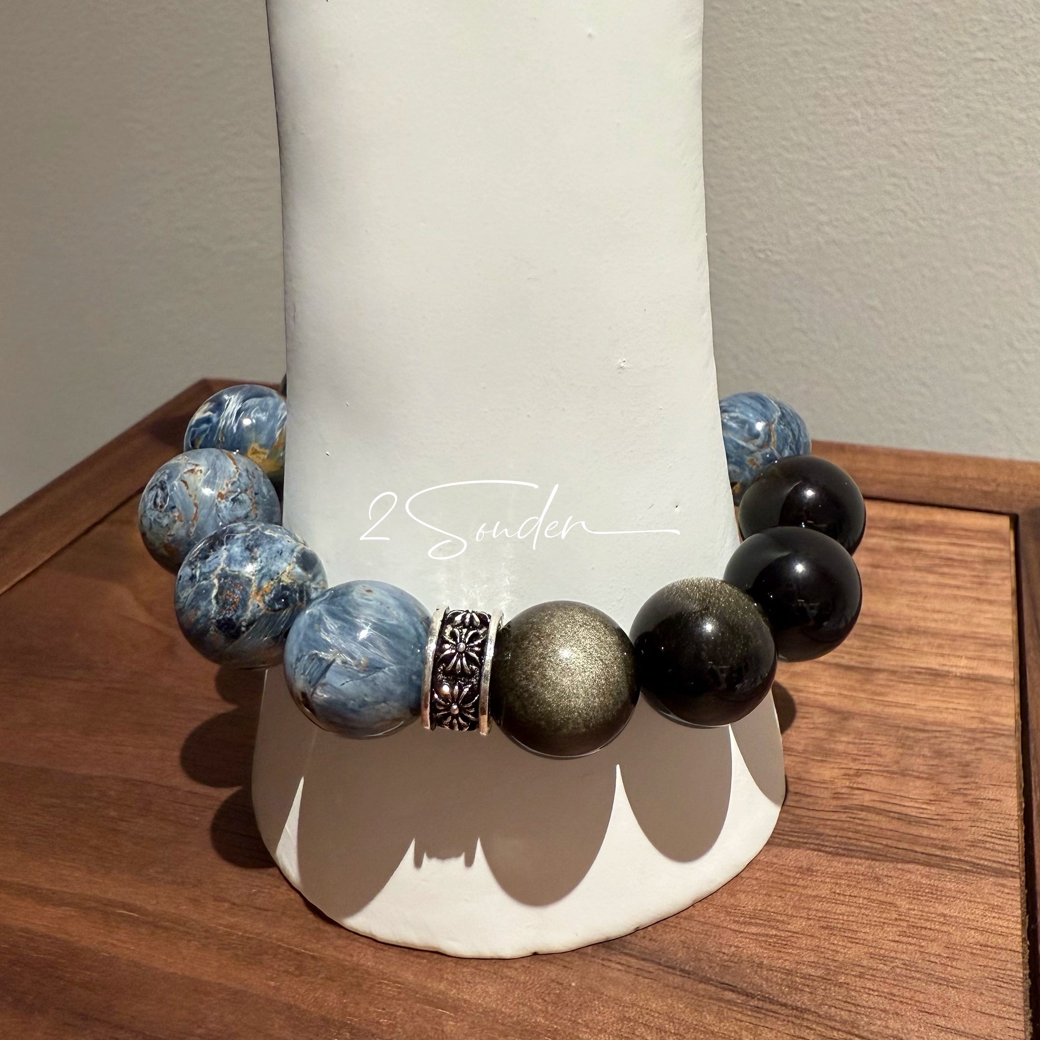 This is a bracelet consists of Blue Denim Pietersite and Golden Sheen Obsidian. The color of the bracelet is denim blue and black, accented by sleek silver spacer.